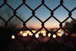  Silhouette  of fence and city lights, out of focus  photo