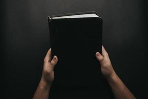 Person holding black book photo