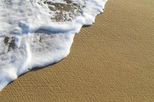 espuma de la orilla del mar en la playa en el sol foto