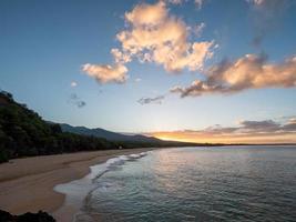 Sea waves crashing on shore during sunset photo