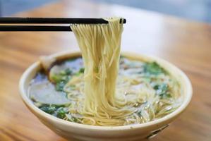 Primer plano de palitos y tazón de ramen foto