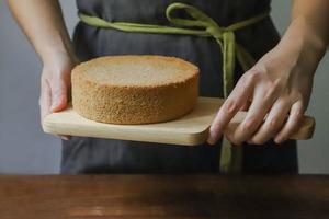 Person holding chopping board with sponge cake photo