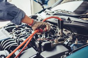 Car mechanic holding jumper cables photo