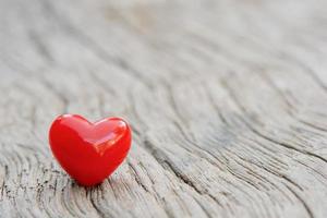 Small ceramic heart sits atop wooden floor photo