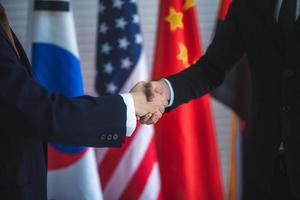 Business people shake hands, international flag background photo
