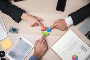 Group of business people point at pie chart photo