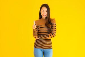 mujer asiática da pulgares delante de fondo amarillo foto