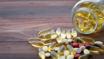 Vitamins and pill bottle on wooden table photo