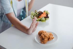 Woman on diet refuses unhealthy food at table photo