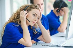 trabajadores de call center estresados frente a computadoras foto