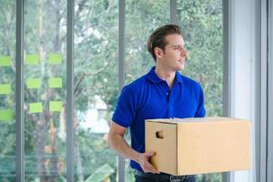 Delivery man holding a package looking away from camera photo