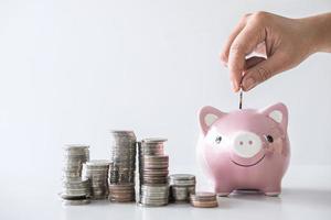 Close-up of hand putting money into piggy bank photo