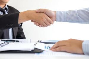 Two people shake hands over documents photo