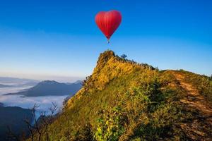 Heart-shaped hot air balloon flies over a mountain  photo