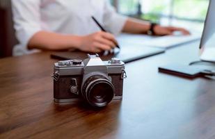 Cámara de cine en el escritorio con mujer editando fotos