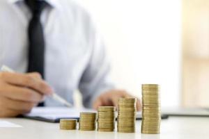 Stack of coins on desk with businessman working in background  photo