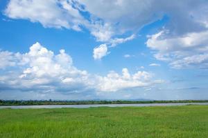Green field with river and blue sky photo