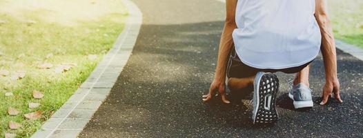 Athlete in running start pose in public park photo