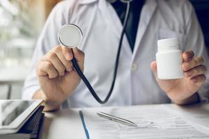 Doctor holding stethoscope and medicine bottle photo