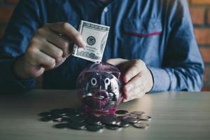 Man putting money into piggy bank photo