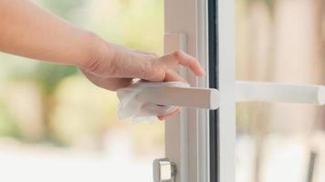 Asian woman using alcohol spray on doorknob at home photo