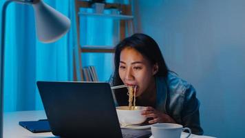 Mujer de negocios independiente asiática comiendo fideos instantáneos mientras trabaja foto