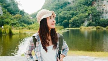 Young  Asian traveler with backpack walking near mountain lake photo