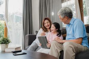 abuelos y nieta asiáticos usando tableta en casa foto