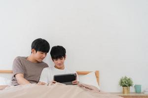 joven pareja gay asiática usando tableta en casa foto