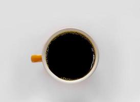 Flat lay view of black coffee in a bright orange cup photo