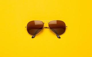 Brown sunglasses on yellow background photo