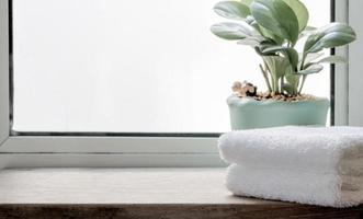 Folded clean towels with houseplant on wooden table photo