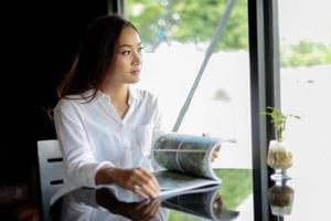 Asian women smiling and reading a book at cafe photo