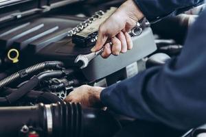 Man using wrench on car engine photo