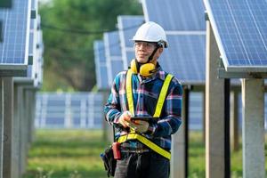 Man wearing safety equipment next to solar panels photo