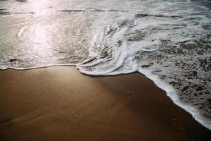 Glimmering waves washing up on beach photo