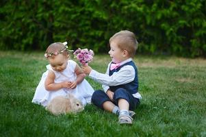 Young boy gives young girl a bouquet of flowers photo