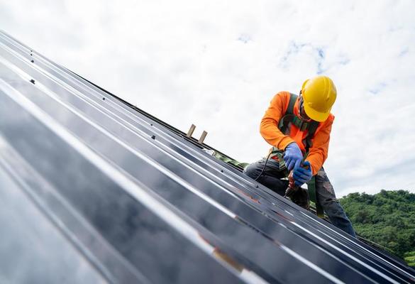 trabajador de techado con uniforme protector y guantes, herramientas para  techos, instalación de techos nuevos en construcción, taladro eléctrico  usado en techos nuevos con láminas de metal. 15632761 Foto de stock en