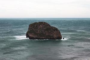 Brown rock formation on sea under white sky photo