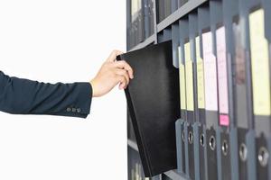 Businessman selecting folder from shelves photo