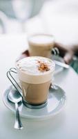 Lattes in clear mugs on saucers photo