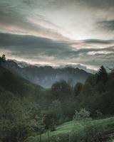 Trees and mountains under a cloudy sky photo