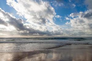 Beach with waves and cloudy blue sky photo