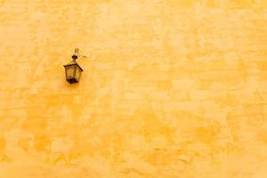 Antique lamp hanging on yellow wall photo