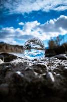 Glass ball on rocks with blue sky