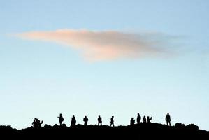 Silhouettes of people on top of a hill photo