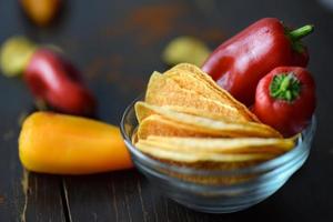 Red chili peppers on potato chips in bowl photo