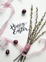 Willow bouquet with Easter sign on white surface photo