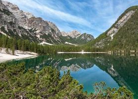 Trees, mountain, and cloudy sky reflected in lake photo