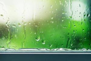 Water droplets streaming down a glass window photo